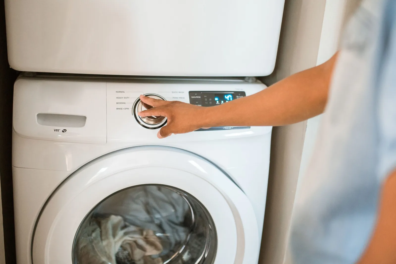 LG appliance repair: hand turning the cycle dial on a front-load washer